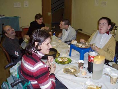 Charo Yago, al fondo de la imagen, da de comer a uno de los discapacitados de un centro madrileño.