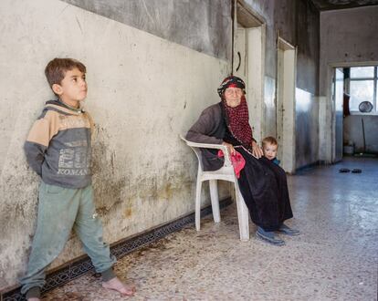 Una abuela con sus nietos en el pasillo de una antigua escuela donde viven los desplazados en un pueblo de la gobernación de Hasake. Los niños sufren las peores consecuencias de los 10 años de conflicto en Siria. De los siete millones de desplazados internos del país, 3,1 millones son menores de edad.