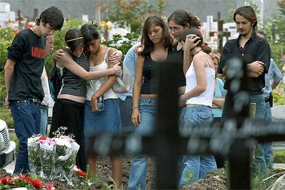 Familiares y amigos de uno de los fallecidos asisten a su entierro en el cementerio bonaerense de Chacarita.