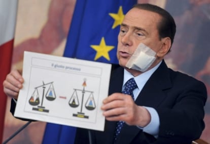 El primer ministro italiano, Silvio Berlusconi, sostiene un dibujo llamado 'El Juicio Justo' en la rueda de prensa posterior al Consejo de Ministros sobre la reforma de la Justicia en Roma.