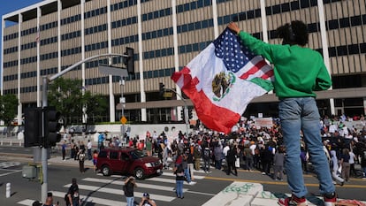 Una persona protesta con una bandera de México y Estados Unidos ante una de las redadas de ICE en el centro de Los Ángeles.