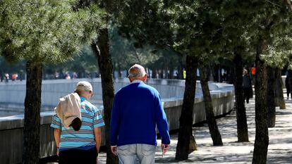 Dos personas de avanzada edad pasean por un parque de Madrid.