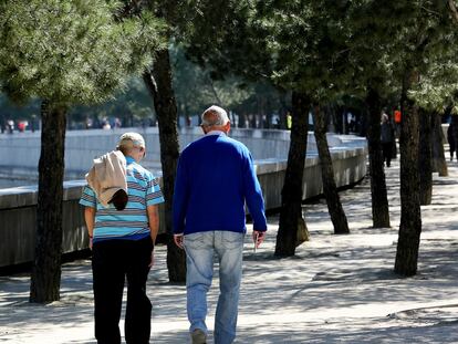 Dos personas de avanzada edad pasean por un parque de Madrid.