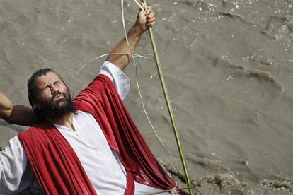 Un hombre que representa a Jesús se sumerge en un río de LIma para representar un bautizo