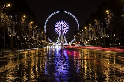 Luces de navidad cuelgan de árboles durante una noche lluviosa en la avenida de los Campos Elíseos, en París (Francia), el 27 de noviembre de 2017.