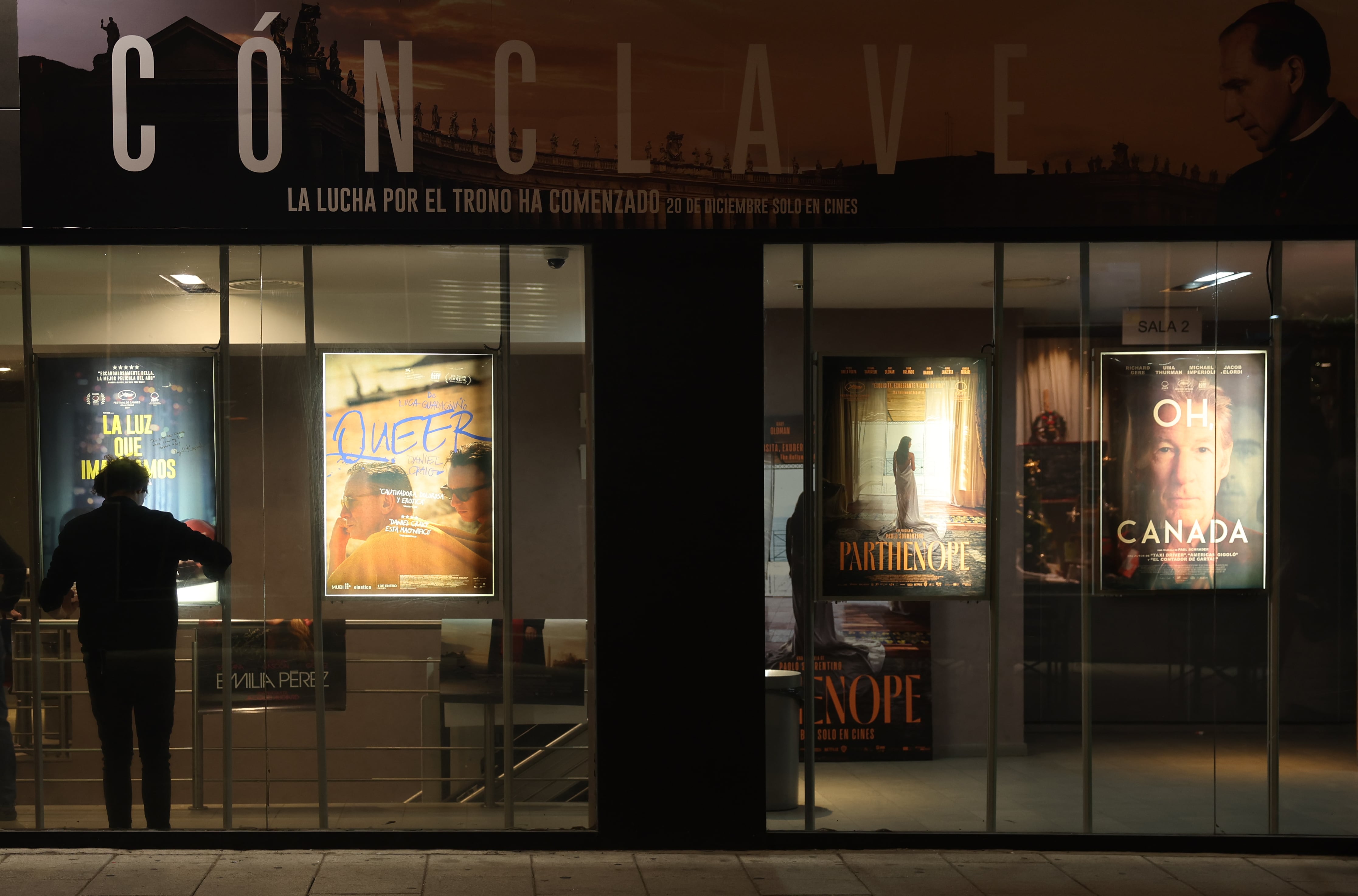 Un trabajador coloca un cartel en la entrada de una sala de cine en Madrid en diciembre de 2024.