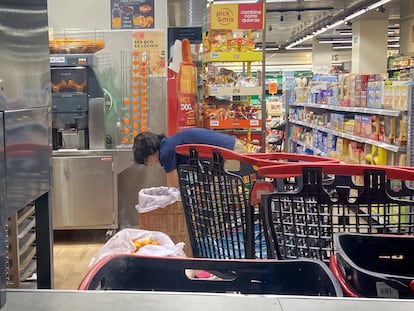 Trabajador de un supermercado tira los restos de comida a la hora del cierre, en julio en Madrid.