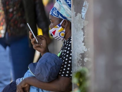 Una mujer consulta su móvil sentada en un banco en Johanesburgo, en Sudáfrica.