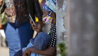 Una mujer consulta su móvil sentada en un banco en Johanesburgo, en Sudáfrica.