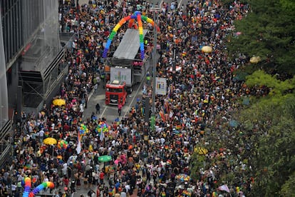 Multitudes festejan junto a un carro alegórico que muestra la temática del 26to desfile del Orgullo en São Paulo: "Vota con orgullo".