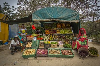 Dieyna Ba posa junto a sus hijos en el puesto de frutas más famoso del barrio de Almadies, en Dakar.