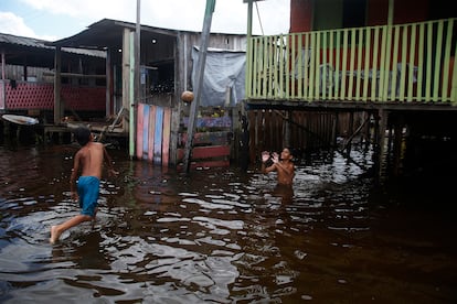 Niños juegan a la pelota en la calle inundada.