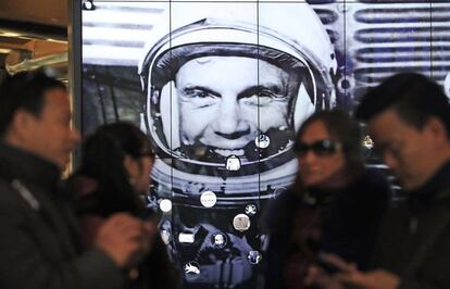 Un gurpo de turistas frente a un retrato del astronauta John Glenn.