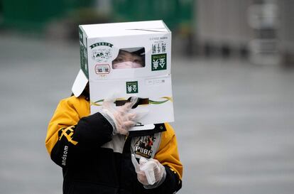 Un niño con una caja de cartón en la cabeza, en la estación de trenes de Shanghai (China).