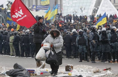 Una manifestante lleva un cazo junto a un cordón de policías antidisturbios en la Plaza de la Independencia en Kiev.