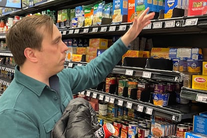 Stuart Dryden reaches for an item at a grocery store on Wednesday, Feb. 21, 2024, in Arlington, Va. Dryden is aware of big price disparities between branded products and their store-label competitors, which he now favors.