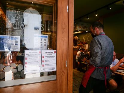 Carteles de indicaciones de obligatoriedad de presentar certificados antes de acceder al interior, en una marisquería de Santiago de Compostela