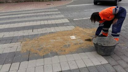 Un operario parchea con arena las juntas de los adoquines en la calle Antón. 