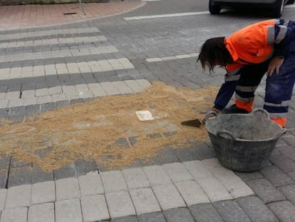 Un operario parchea con arena las juntas de los adoquines en la calle Antón.