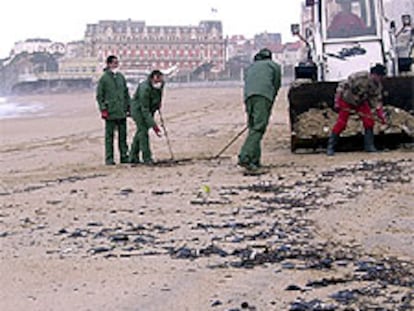 Trabajadores del Ayuntamiento de Biarritz (suroeste de Francia) limpian las <b></b><i>galletas</i> de fuel del <b></b><i>Prestige</i> llegadas ayer a la playa.