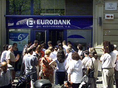 Decenas de clientes de Eurobank hacen cola, ayer, en una de las oficinas de Barcelona para retirar sus ahorros.