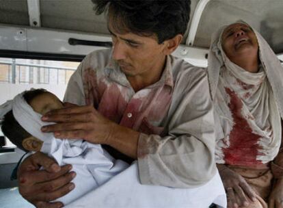 Un hombre cierra los ojos de su hija, muerta en el atentado de Peshawar, mientras la abuela de la niña, con la ropa ensangrentada, llora.