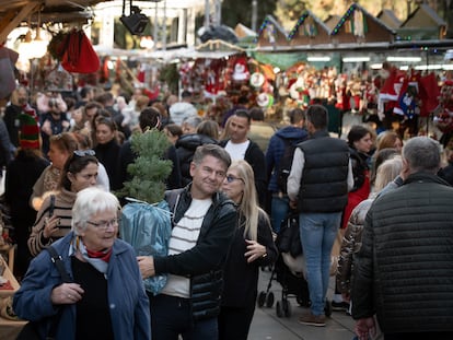 Varias personas realizan compras en el mercado navideño de la Fira de Santa Llúcia, en Barcelona.