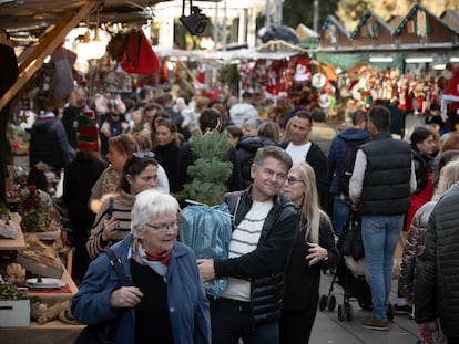 Varias personas realizan sus compras navideñas en el mercado navideño de la Fira de Santa Llúcia.