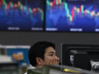 Un empleado surcoreano de la Bolsa de Seúl trabaja junto a varios monitores que muestran la evolución del índice referencial del Kospi, en la sede de la Bolsa de Seúl. EFE/Archivo