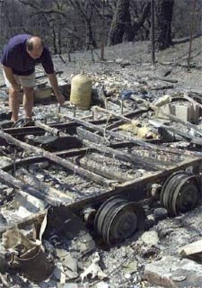 Un hombre observa los restos carbonizados de su vehículo.