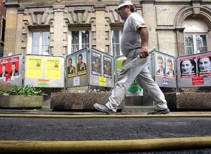 Un pintor pasa ante los carteles electorales en Noisy Le Sec, al norte de París.