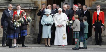 La reina de Inglaterra y el Papa reciben unos ramos de flores de manos de unos escolares a las puertas del palacio de Holyroodhouse.