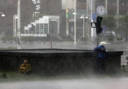 Dos motoristas buscan refugio ante el intenso azote de las rachas de viento y la lluvia provocadas por el supertifón Meranto en Kaohsiung (Taiwán).