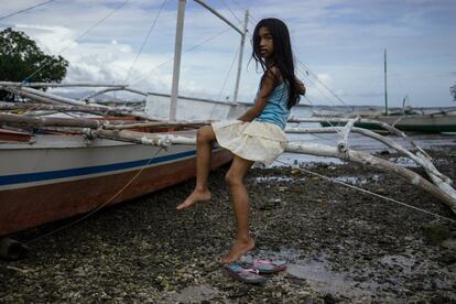 Una niña posa sentada en un banka, en una playa de Taytay.