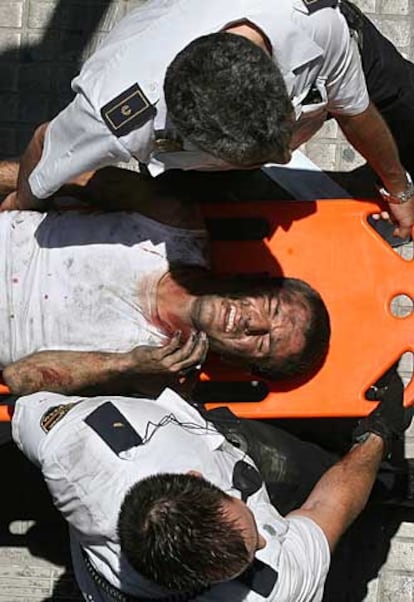 Dos policías ayudan a llevar a uno de los heridos en el accidente del metro de Valencia.