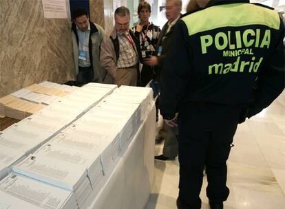 Un policía local pasa junto a una mesa con las papeletas de votación en el colegio San Agustín de Madrid. Unos 35 millones de españoles están llamados a las urnas para decidir la composición del Congreso y el Senado de la VIII legislatura.