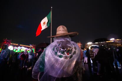 Un hombre se protege de la lluvia con una bandera en el Zócalo de Ciudad de México.