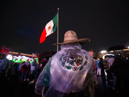 Un hombre se protege de la lluvia con una bandera en el Zócalo de Ciudad de México.