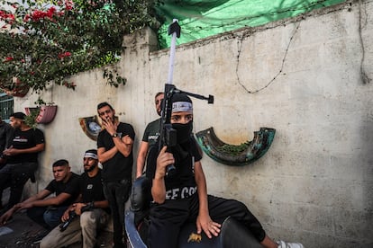 Un niño encapuchado muestra un arma de plástico durante un funeral en Yenín, Cisjordania.