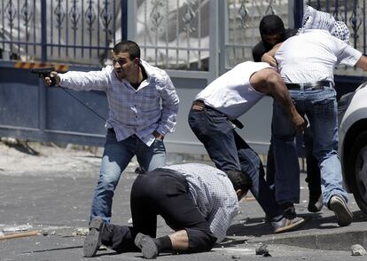 Policías secretos israelíes, uno con una pistola, arrestan a un palestino durante los enfrentamientos tras la oración del viernes cerca de la ciudad vieja en Jerusalén Este.