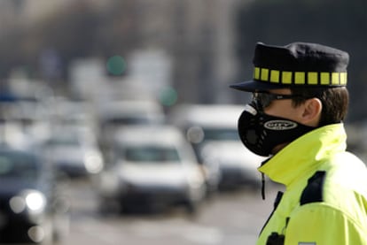 Una densa nube negra de contaminación cubre Madrid desde el pasado 29 de enero. En la imagen, un guardia de tráfico, ayer en el centro de la capital.