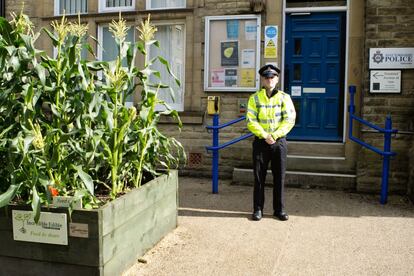 El oficial de policía Matt Hamilton posa junto a las florecientes plantas de maíz dulce en la entrada a la comisaría de Todmorden.