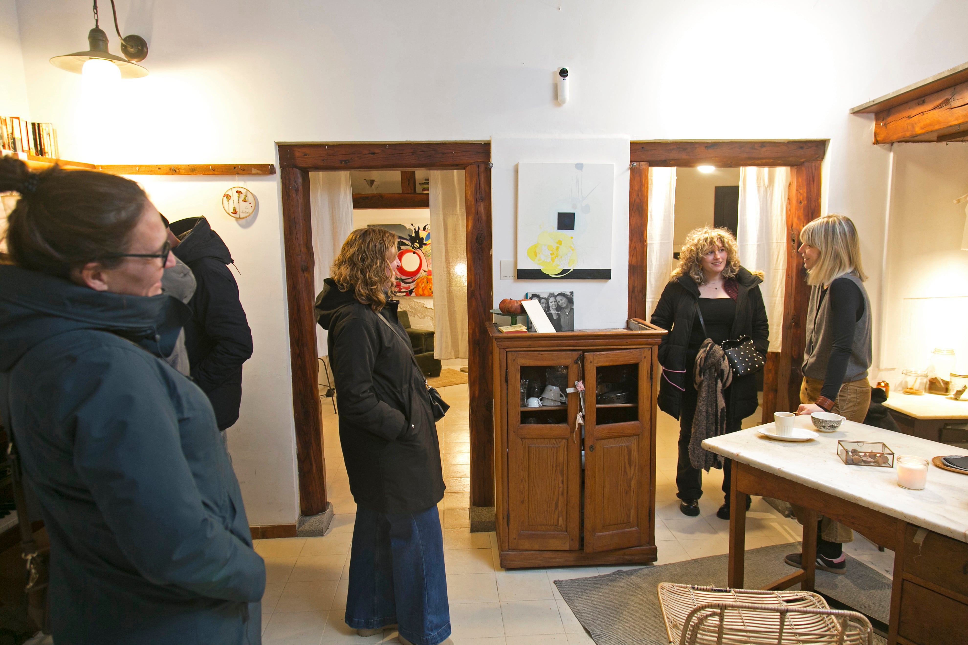 Verónica charla con varias personas que han entrado a curiosear en La Botería. En el interior se ven un par de cuadros del artista Seann Bracking, socio número 138.