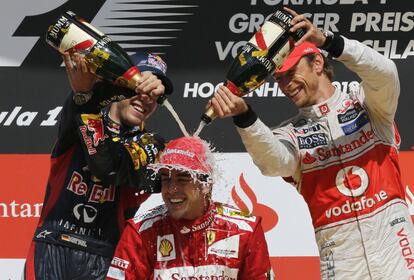 Alonso es mojado con champaña en el podio por Vettel y Button, tras su victoria en el GP de Silverstone (Inglaterra),