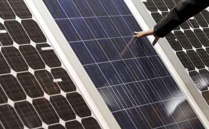 Un hombre toca la superficie de unas placas solares.