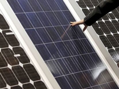Un hombre toca la superficie de unas placas solares.