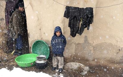 En la imagen, un niño permanece de pie en la puerta de su casa de barro durante una nevada en las afueras de Srinagar, en Cachemira (India).