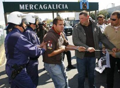 La policía intenta romper el cerco de cadenas que los ganaderos formaron ayer en los accesos a Mercagalicia, en Santiago.