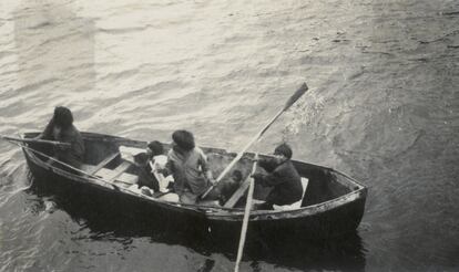 Personas Kawésqar se trasladan en bote en un fiordo.
