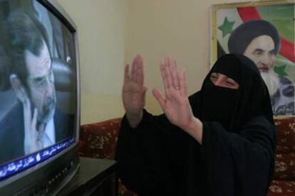 Una mujer chi, con una foto del ayatol Al Sistani a su espalda, durante la retransmisin del juicio a Sadam.